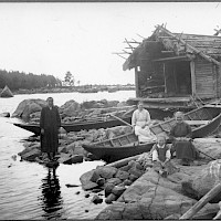 Women at a fishing harbour in the village of Västerö, Maxmo. Boats and sheds by the shore. 1920’s–1930’s.   Photographer: Erik Hägglund.  Archive collection: The Society of Swedish Literature in Finland (SLS), sls.finna.fi SLS 865 B 133