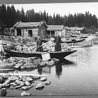 Fishing harbour in the village of Österö, Maxmo. Three women by the shore, boats and sheds. Photographer: Erik Hägglund. Archive collection: The Society of Swedish Literature in Finland (SLS), sls.finna.fi SLS 865 B 179