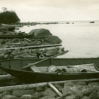 Fishing harbour in the village of Österö, Maxmo. Boats pulled ashore on logs, sheds.   Photographer: Erik Hägglund.  Archive collection: The Society of Swedish Literature in Finland (SLS), sls.finna.fi SLS 865 B 180