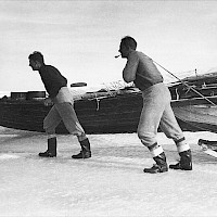 The seal hunting boat is being hauled out onto the ice. The hunting party first pulled the seal hunting boat some distance on the fast ice and then went back to fetch the seal hunting dinghy. A three-man sealing party managed with one dinghy, whereas a four-man party took two dinghies out on an expedition.   Photographer: Erik Bengs 1959 Archive collection: Kvarken Boat Museum, picture archive