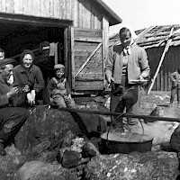 Seal meat being boiled in the harbour of the village of Norra Vallgrund in 1962. The blubber was scraped off the skin and then cut into shreds, which were cooked for almost an entire week. Once the blubber had melted, it was poured into barrels. Hot blubber was flammable and care had to be taken to prevent fires. If a fire did break out, water could under no circumstances be used to extinguish the flames – that would only spread the fire. During a day or two, all the seal meat was boiled down in the harbour. Cooking time varied between one and a half and two hours. Meat from a cub would cook faster than meat from an older animal. The flippers, too, were cooked. The skin was then peeled off and the flippers, which had turned white, were eaten. Seal meat was sold in town, first at the Vaasa market place and later in the fish market down by the town harbour.  Photographer: Göta Bengs Archive collection: Kvarken Boat Museum, picture archive